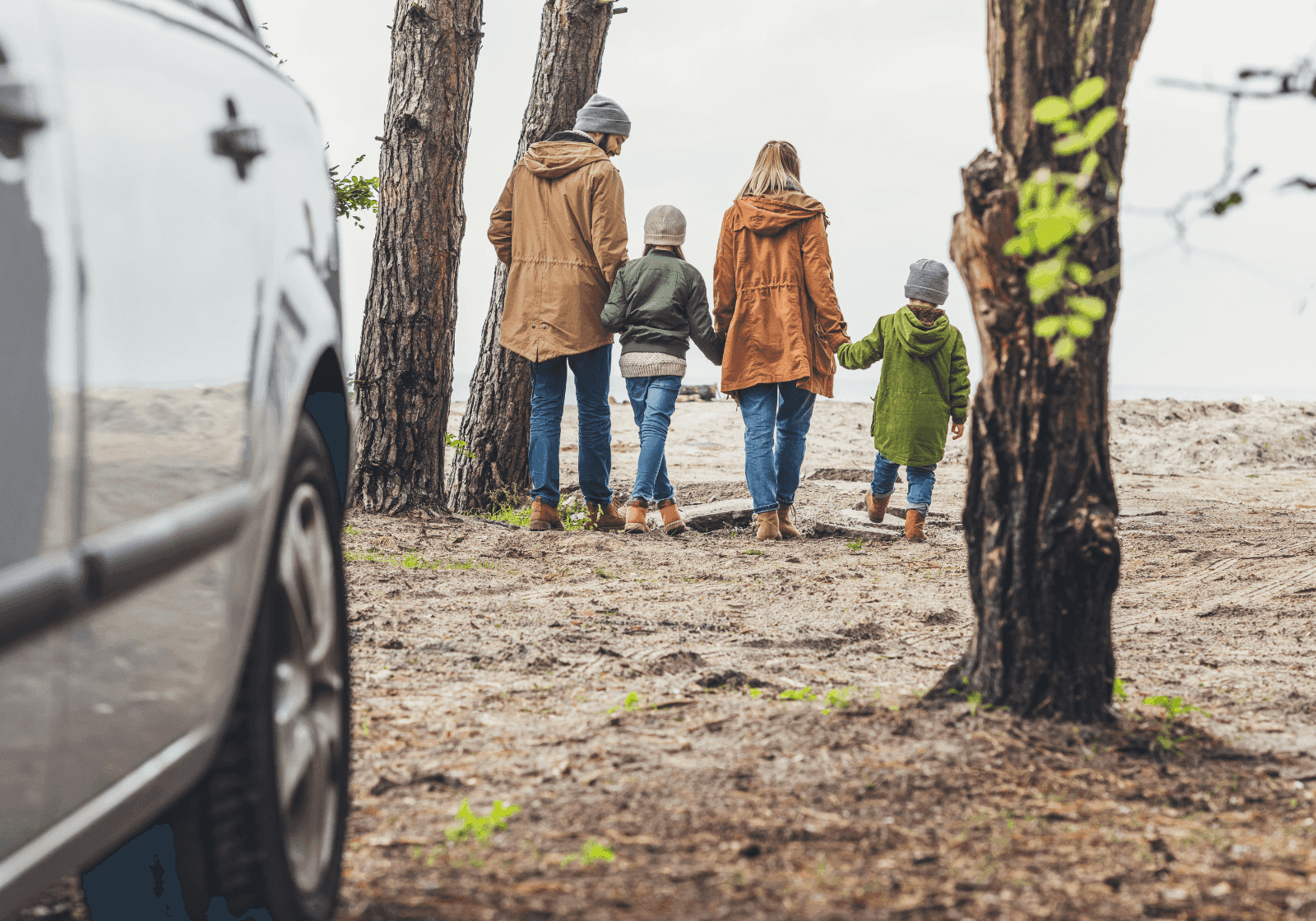 Familie går fra deres bil og ud i en skov